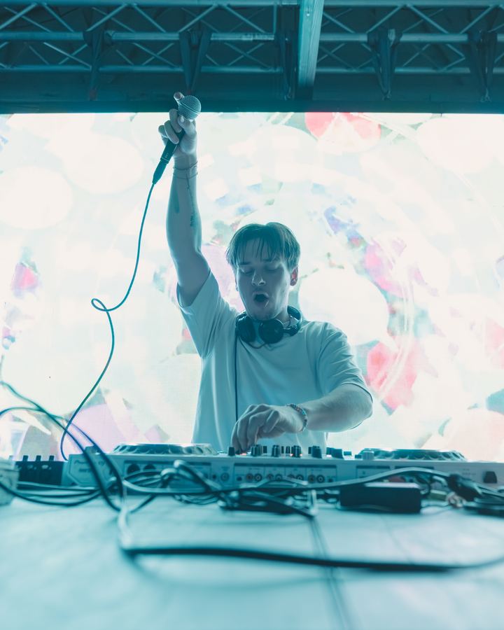 DJ behind the decks in front of a bright screen