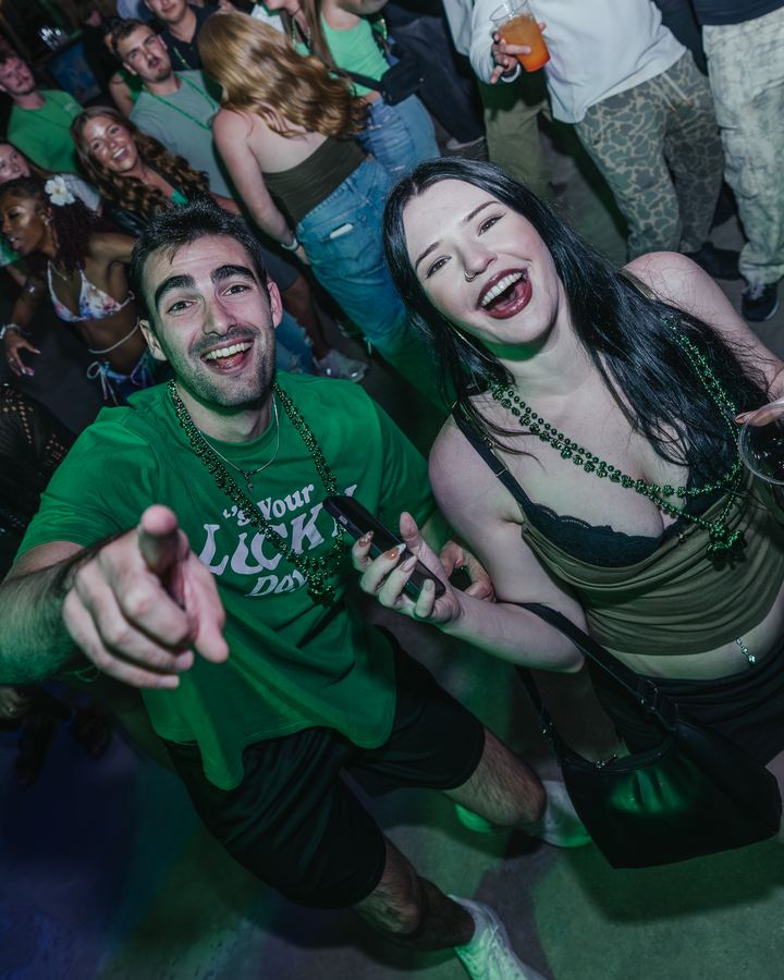 Couple in green pointing at the camera